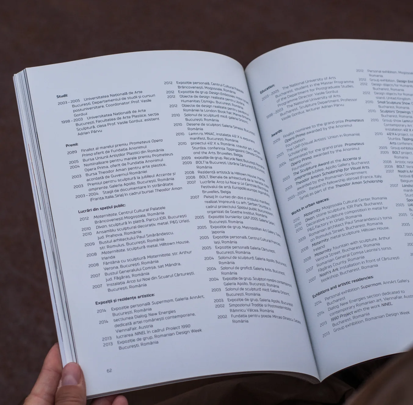 Hands holding the open art catalogue: a line drawing facing a photograph of a bronze sculpture